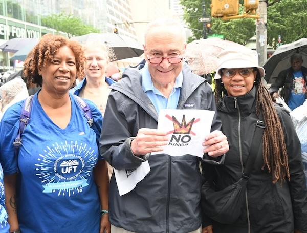 Image of Senator Schumer and two women at No Kings protest. Senator Schumer is holding a sign.